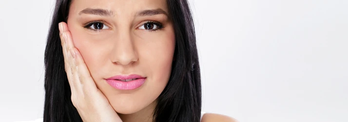 A woman holding her jaw with TMJ pain