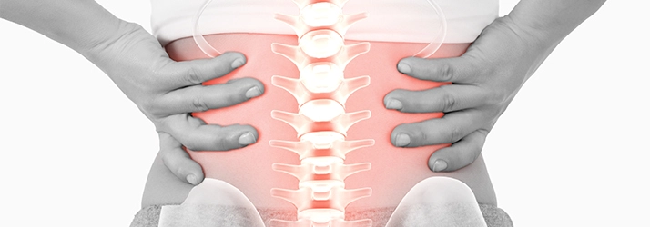 A person holding their back. Their spine is highlighted pink.