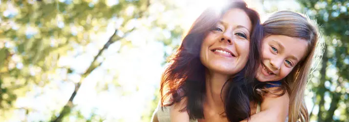 A mom giving her daughter a piggy back ride.