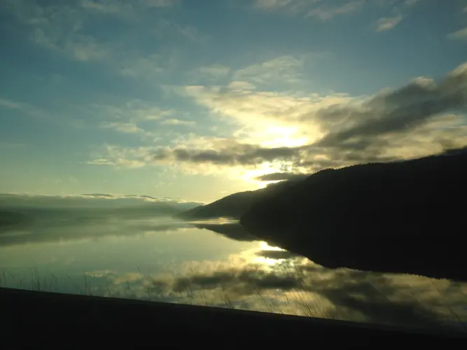 A scenic view of the sun setting over a lake