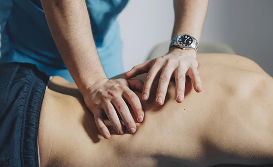 A massage therapist performing deep tissue massage on a patient's back