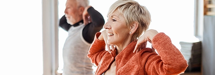 A senior couple doing aerobic exercises in their living room