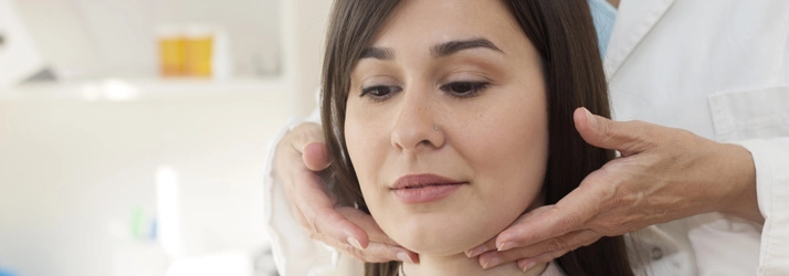 A doctor consulting with a female patient and examining her jaw